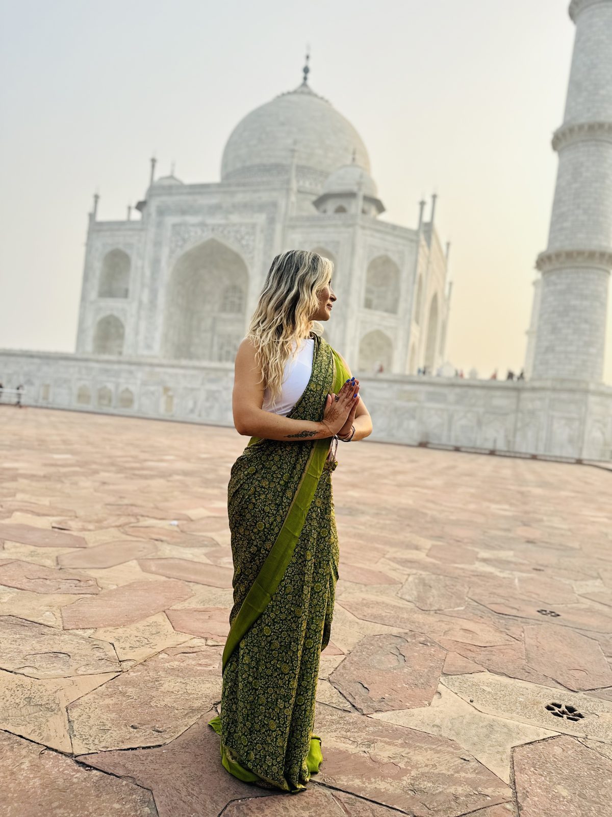 Olga en India con un sari verde y las manos en el pecho